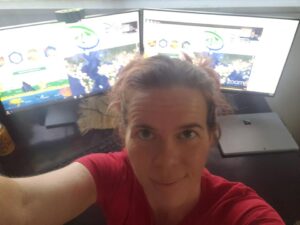 selfie of a person with two computer monitors behind them