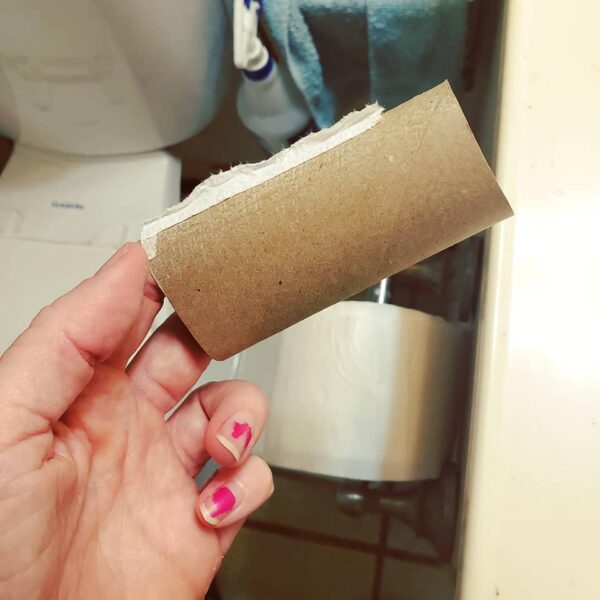 a hand holding an empty roll of toilet paper