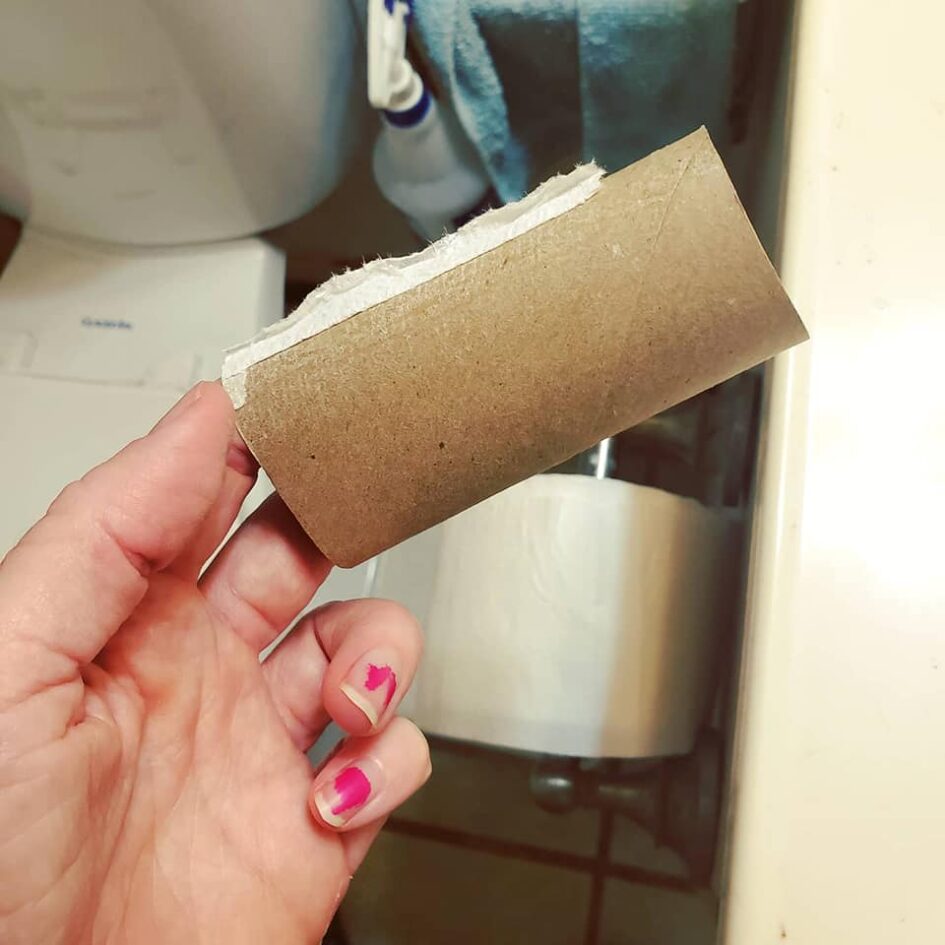 a hand holding an empty roll of toilet paper