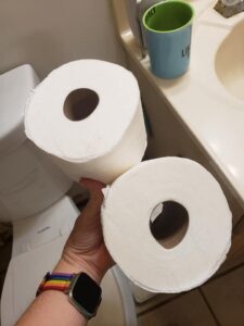 a hand holding two new rolls of toilet paper