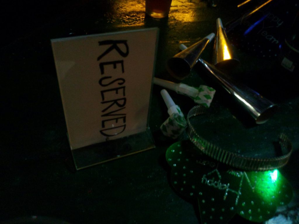 a dark table surface with a reserved sign and some new years eve horns and hats