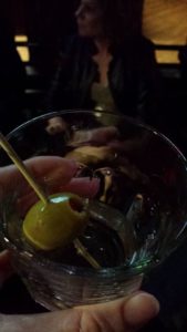 close up of a glass with a cocktail olive in it