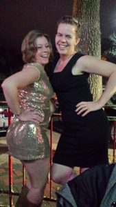 two girls posing for the camera, one wearing black and the other wearing sparkling gold