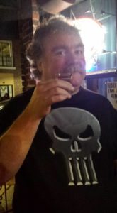 a person in a bar raises a shot glass cheerfully