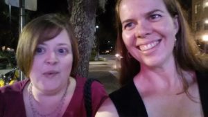 two people looking into the camera but noticeably looking off the side with a dark city view behind them