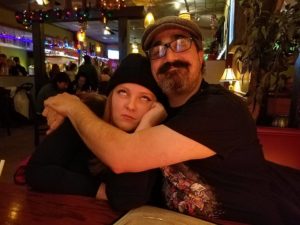 two people in a restaurant hugging while one smiles and one rolls her eyes