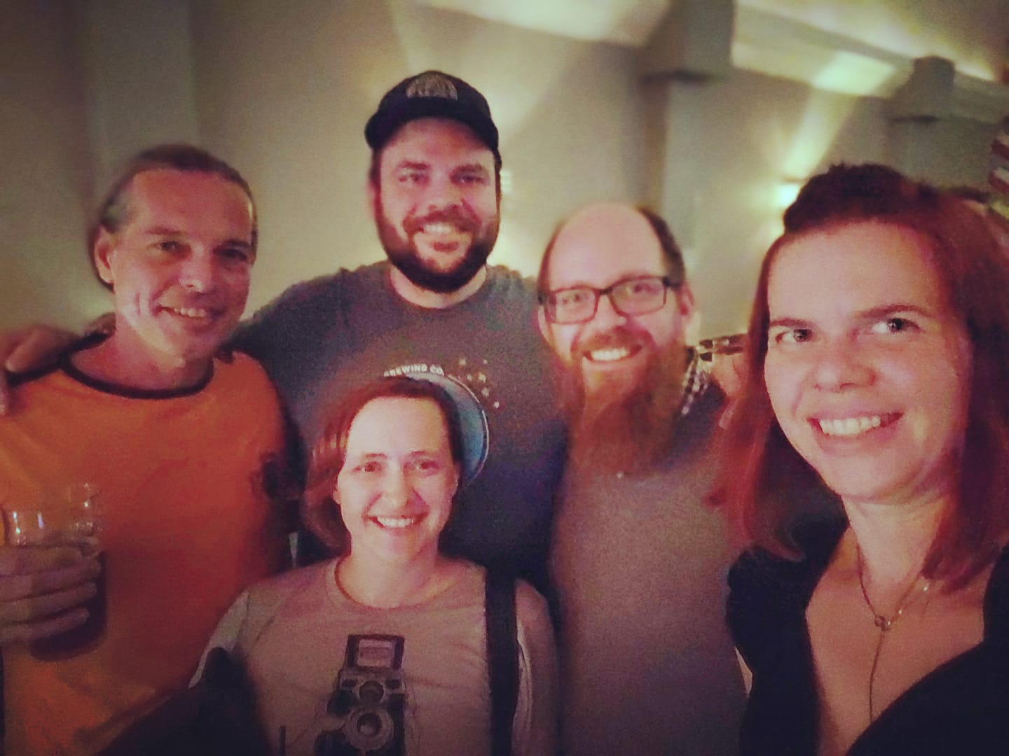 a group of people in a dark bar posing for a smiling photo