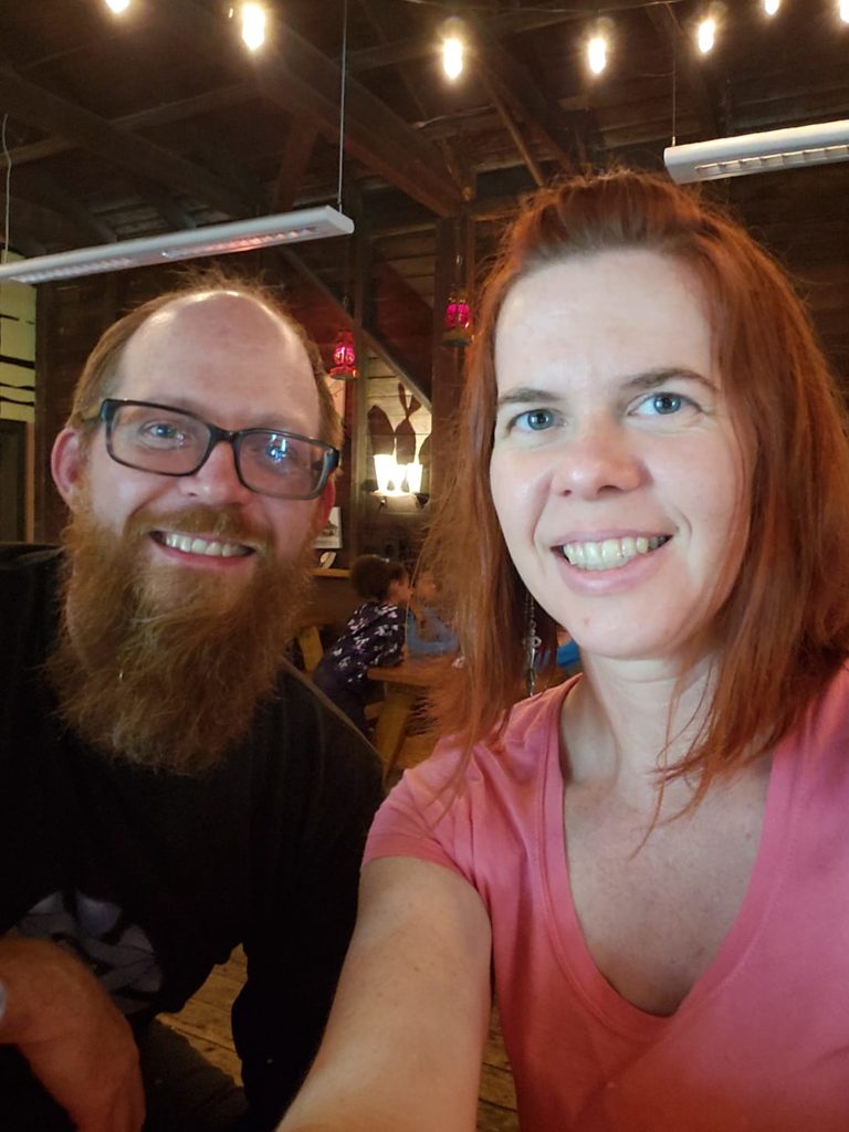 a selfie of two people, one with shoulder length red hair and the other with a long red beard