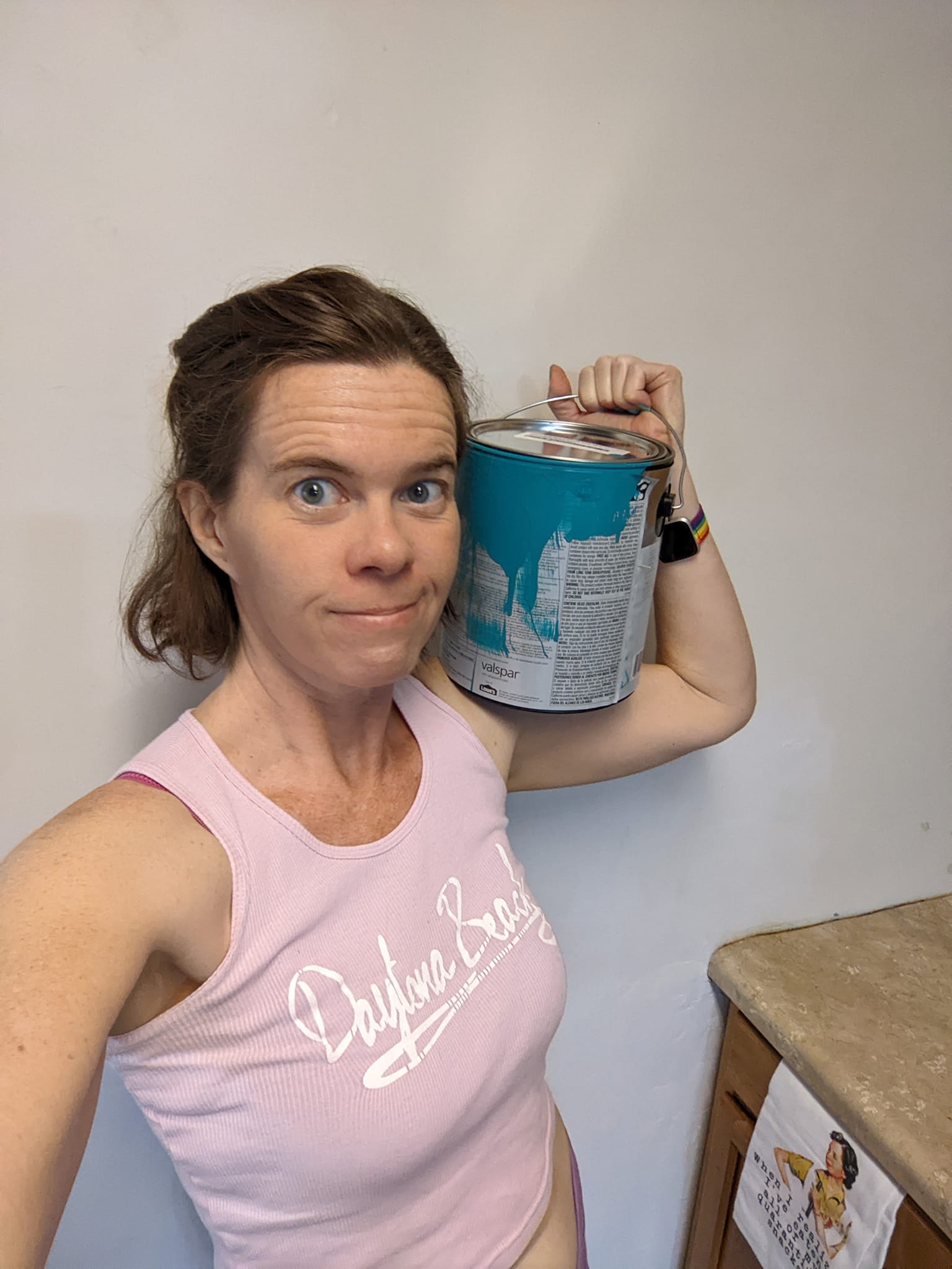 selfie against a white wall holding a can of teal blue paint