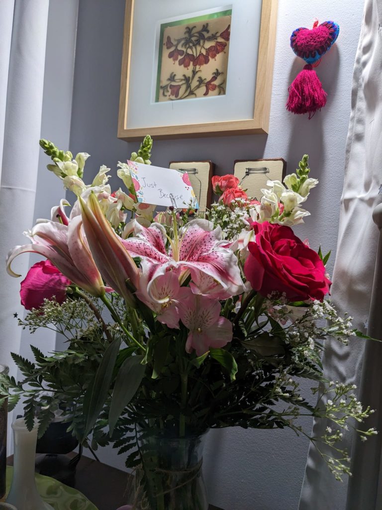 a bouquet of roses and lilies under bright light against a grey wall
