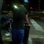 a person leans over a city trash can on a night street corner