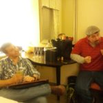 two people sit in a bright hotel room next to a table with champagne and glasses