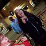 several people smoke cigars and laugh on a bar patio on a street corenr