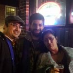 three people on a dark bar patio pose for a silly photo