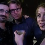 three people in almost darkness pose for a picture with one sticking their tongue out