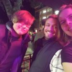 three people on a dark city corner post for a photo smiling