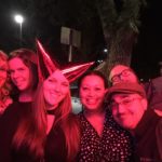 a group of new years partiers pose for a photo under dark red light