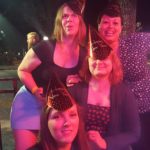 a selfie of four people in new years hats under strong red light