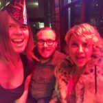 a selfie of three people in new years hats under strong red light