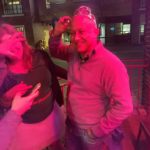 a person on a bar patio is laughing and putting a tiara on