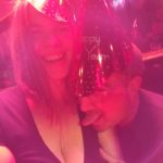 a selfie of two people in new years hats under strong red light