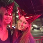 a selfie of two people in new years hats under strong red light