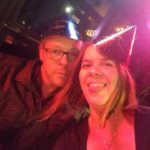 a selfie of two people in new years hats under colorful bar lights
