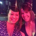 two people with new year's even hats on pose under harsh red light
