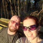a selfie of two people on a bench in the woods with bright sunlight on them