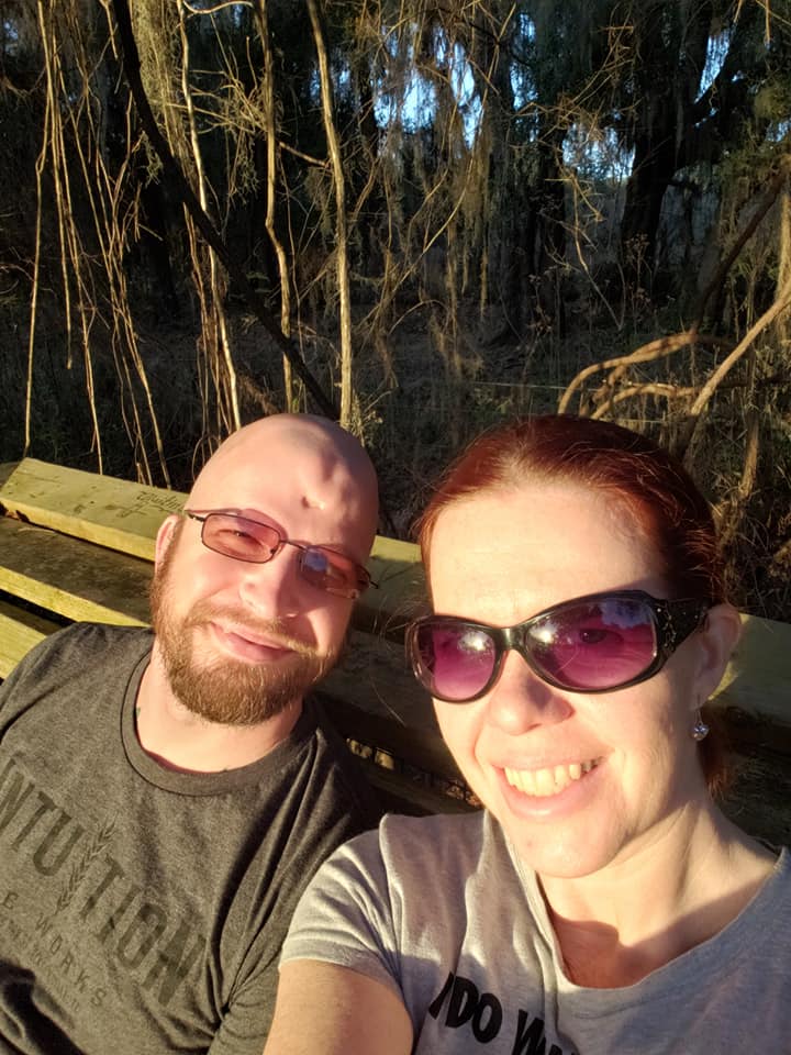 a selfie of two people on a bench in the woods with bright sunlight on them