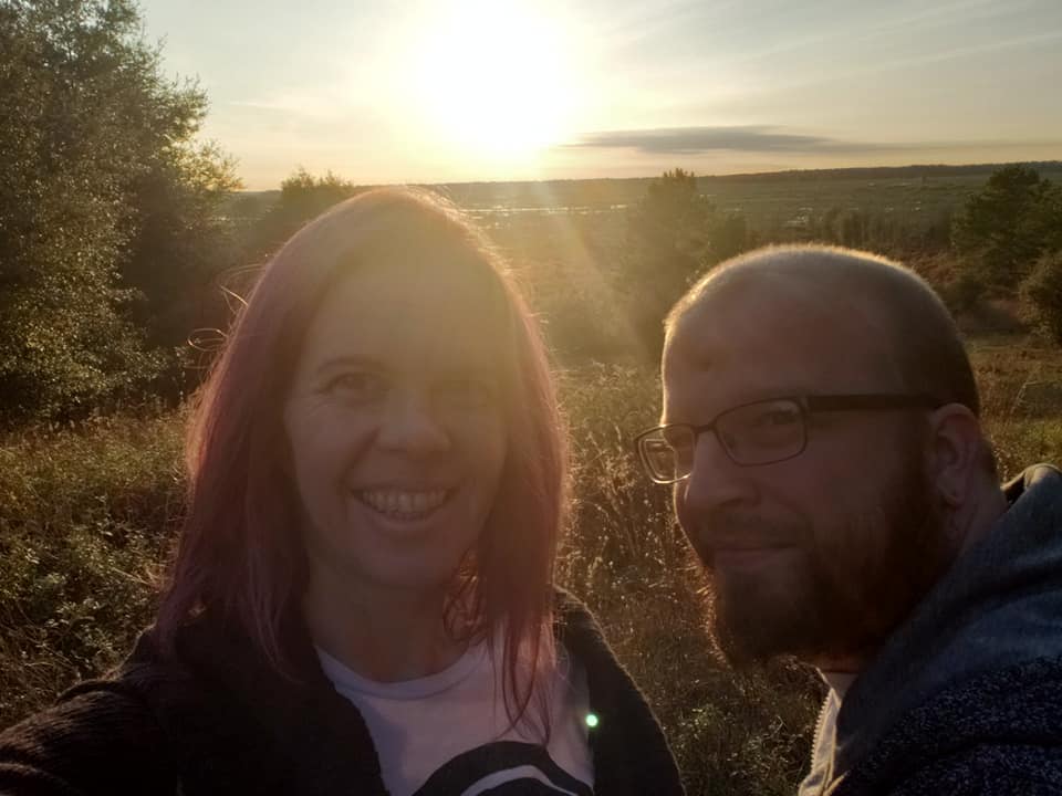 two people in silhouette against the setting sun with an open prairie behind them