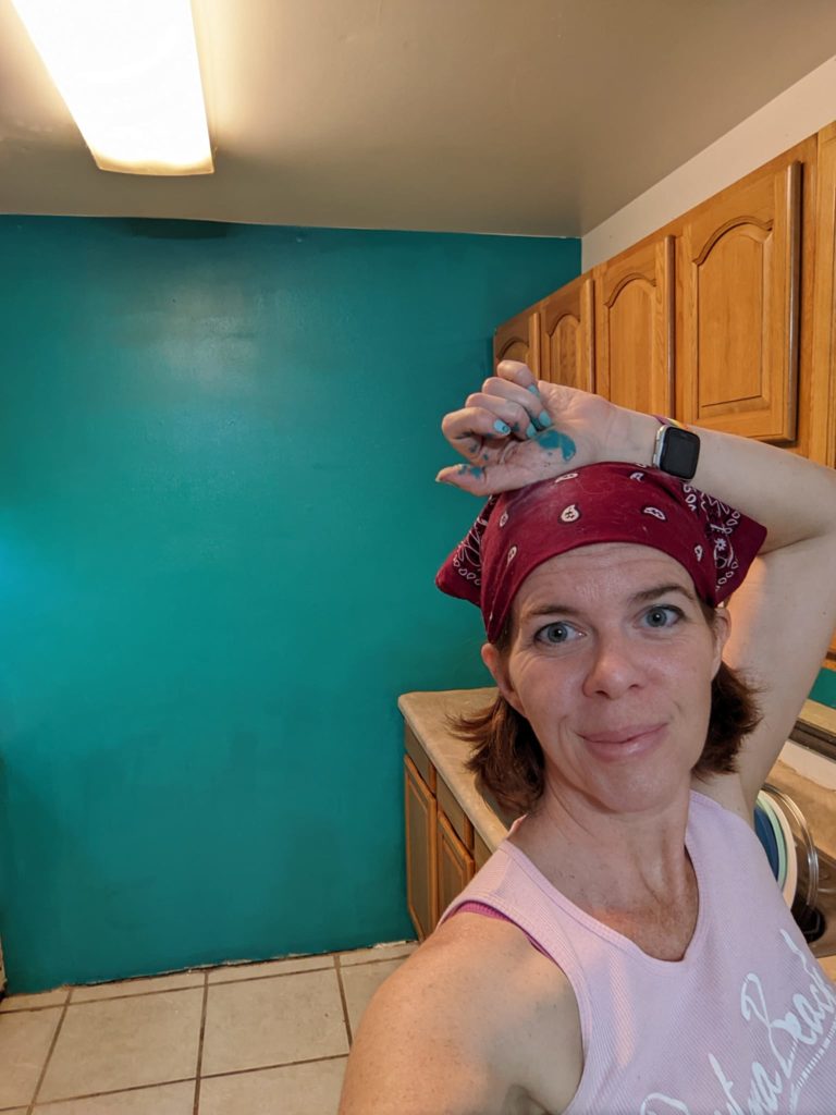 a person with a scarf on their head poses in front of a newly painted wall