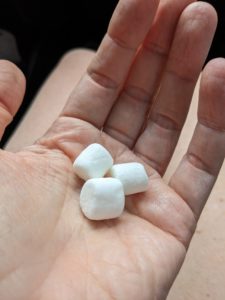 a hand holding three small marshmallows