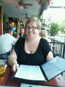 a person holding a menu at an outside restaurant table