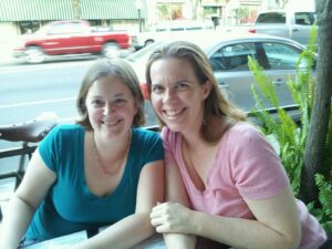 two people at an outside dining table smiling for the camera