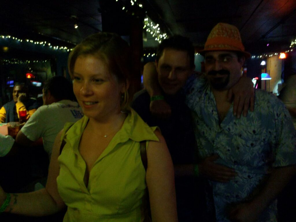 three people in a dark bar stare intently off camera