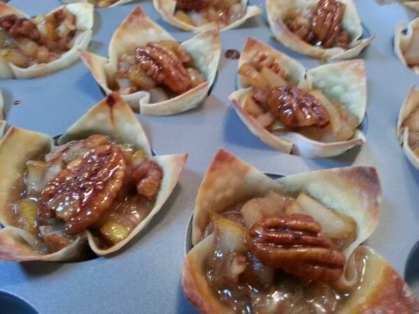 rows of little pastries topped with fruit and nuts are baked to golden brown