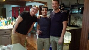 three guys pose for a group shot, all wearing black t-shirts and khaki pants