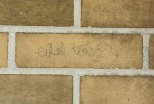 a brick wall with pencil writing saying eiffel tower