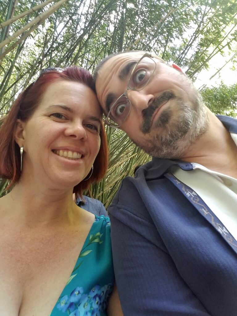a selfie of two people dressed up in front of bamboo