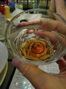 looking down into a glass shot glass with brown liquid in it
