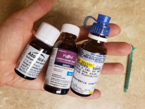 three small bottles of medication in a hand