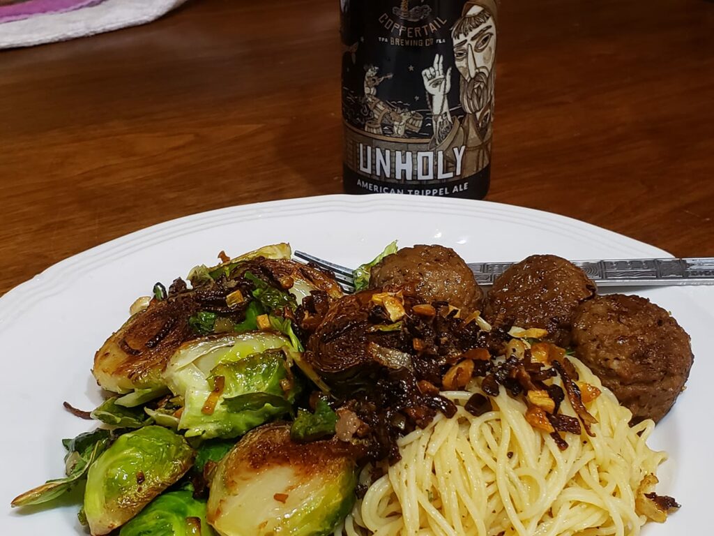 a dinner plate with pasta, brussel sprouts and meatballs