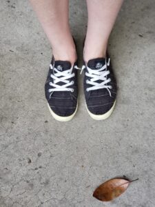 looking down at a pair of feet in black cloth shoes