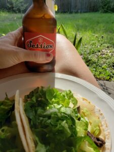 a salad and a beer held in hands on a lap