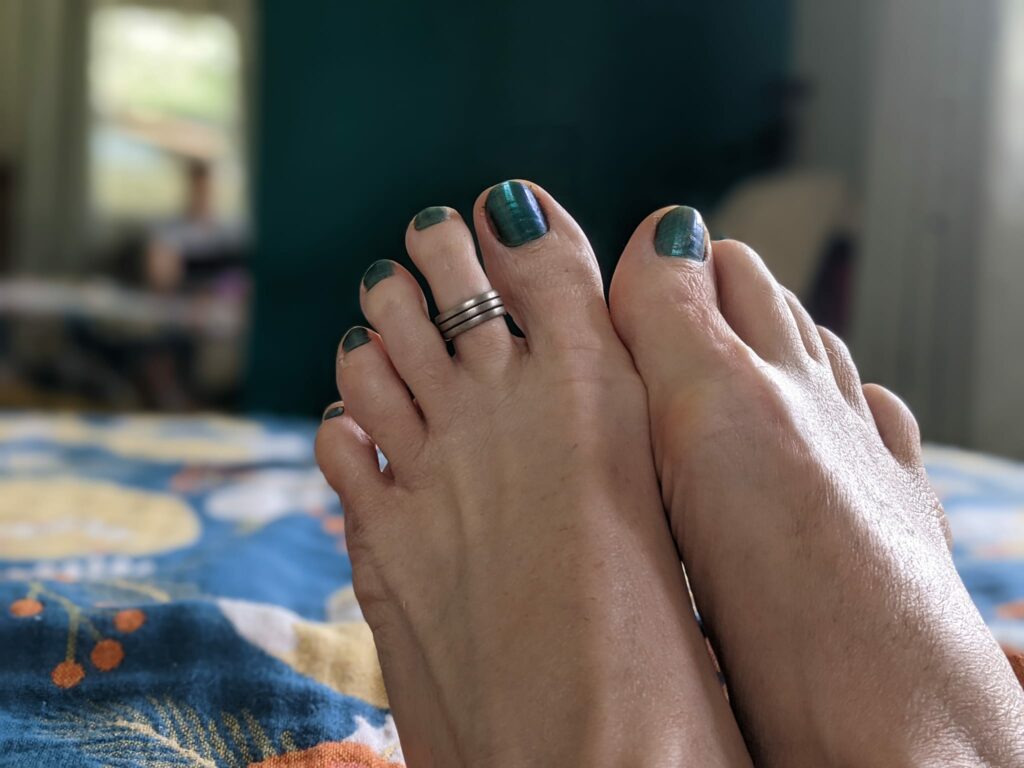 a picture of feet with teal nail polish the same as the wall in the distance
