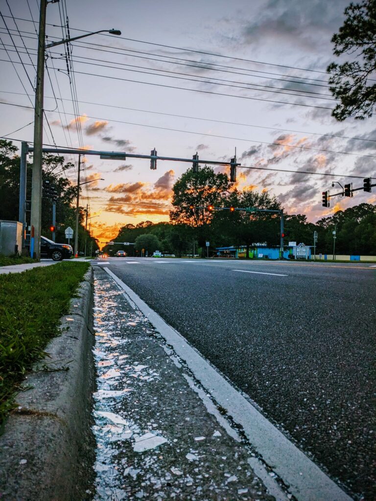 a street view under a bright sunset with broken glass in the gutter