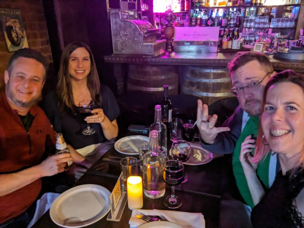 a group of four people sitting around a very full table in a restaurant