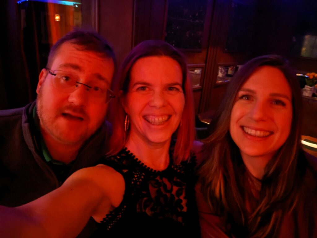 a selfie of three people in a very red light