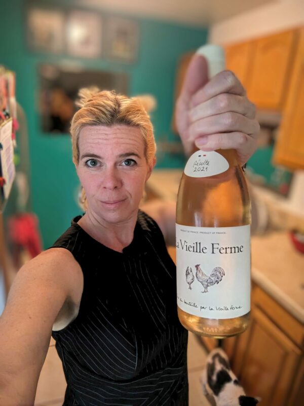 a selfie of a person holding a wine bottle towards the camera